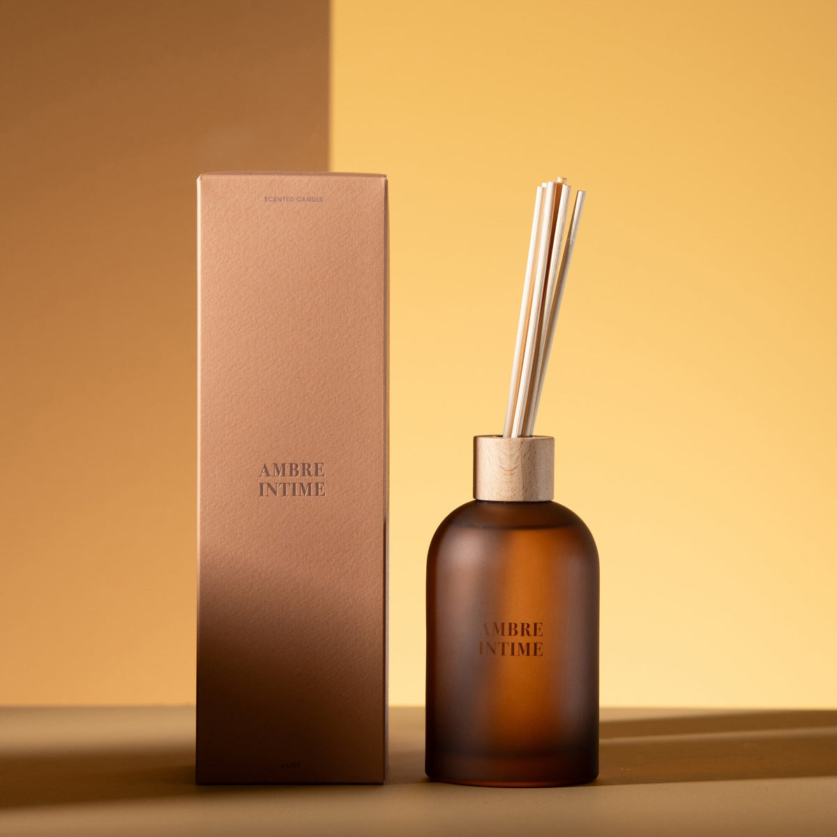 Geurstokjes Accords Essentiels Ambre Intime 250ml van J-Line met bijpassende doos in een sfeervolle okerkleurige setting