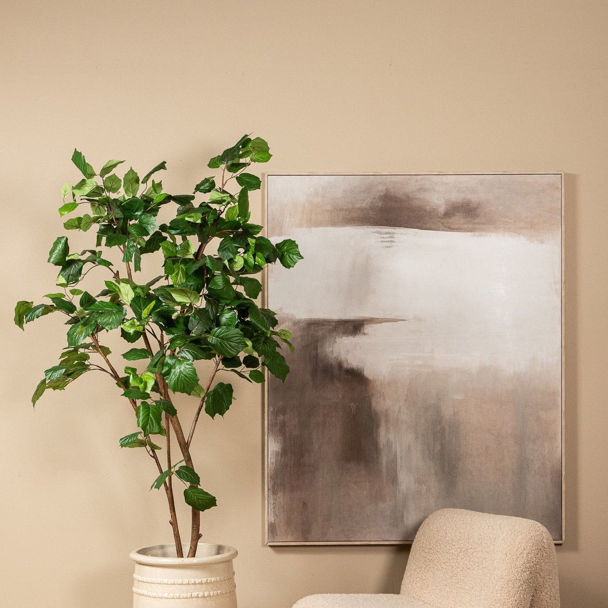 Kunstboom met druivenbladeren van PTMD in een woonkamer naast een fauteuil